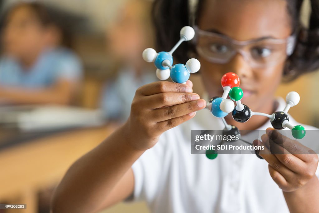 Elementary science student using plastic atom model educational toy