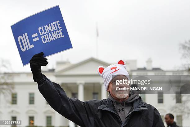 An environmental activist holds a placard during a rally in front of the White House on November 29, 2015 in Washington, DC. Leaders from around the...