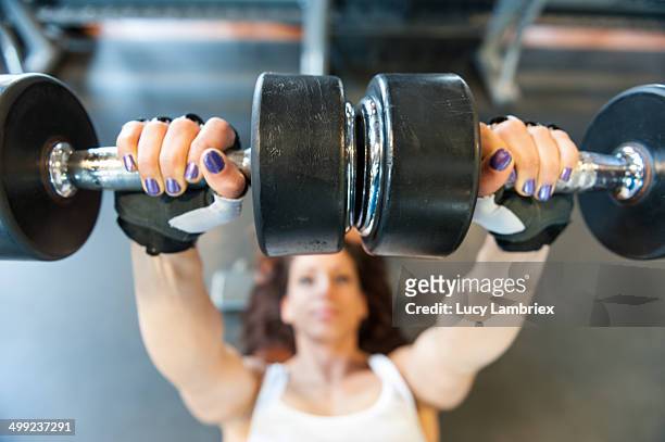 young woman at gym working her arms with dumbbells - images of female bodybuilders stock pictures, royalty-free photos & images