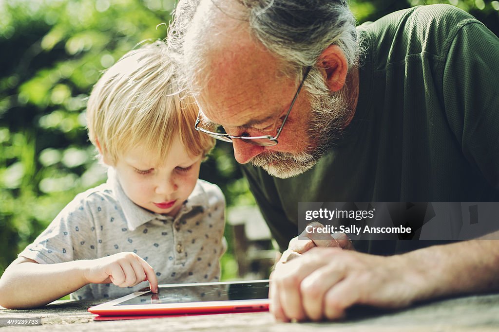 Child using a tablet with his Grandpa