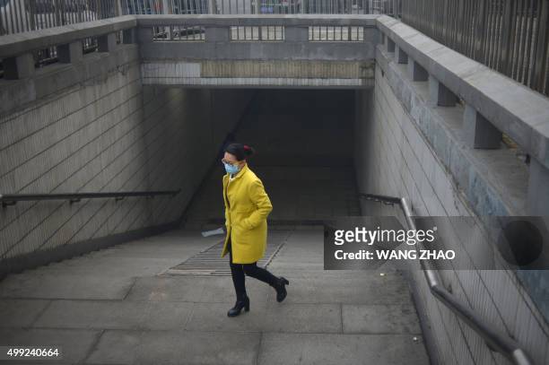 Woman wearing a mask exits an underpass in Beijing on November 30, 2015. Beijing choked under the worst smog of the year on November 30, with...