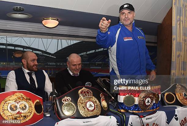 Britain's world heavyweight champion Tyson Fury and trainer and uncle Peter Fury listen as John Fury talks during a press conference in Bolton, north...