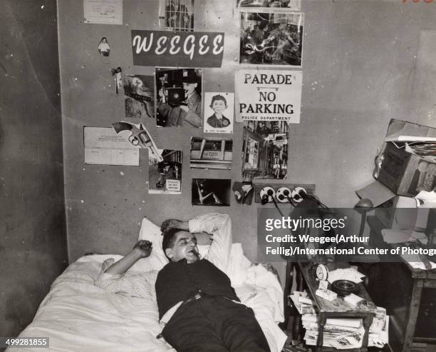 American photographer Arthur Fellig, better known as Weegee lies on his bed, eyes clsoed and a cigar in his mouth, in a photograph entitled 'My...