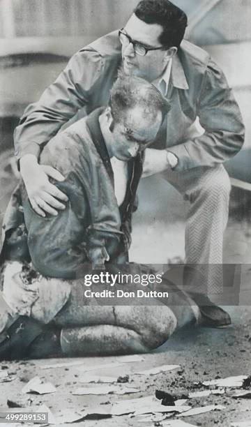 Injured when a bank robber was blown to bits by his own bomb; Constable Don Milliard sits in a Kenora street; comforted by Constable Ken Richardson...