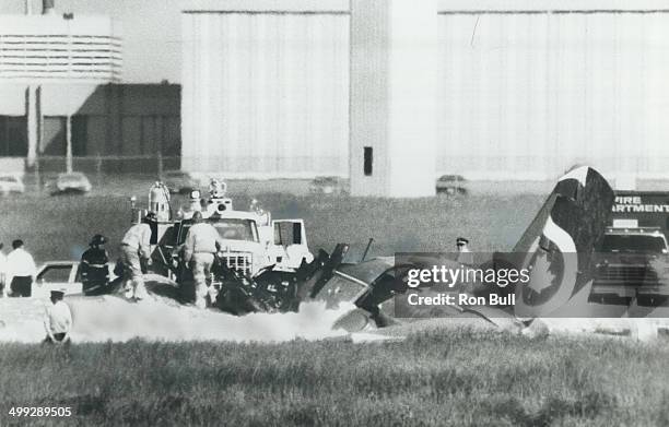 Airport firefighters pour chemical foam on wreckage of twin-engined cargo plane that crashed at Malton airport today; killing the two-man crew