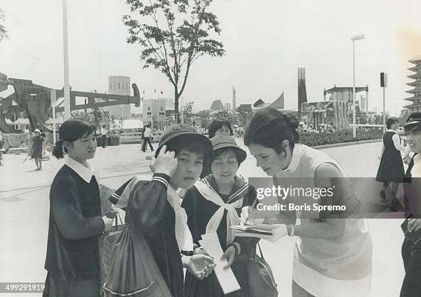 Signing autographs at Expo 70 in Osaka; Japan; is one of the major tasks of Cathy Fauquier; 25; of Toronto; one of the hostesses at the Ontario...