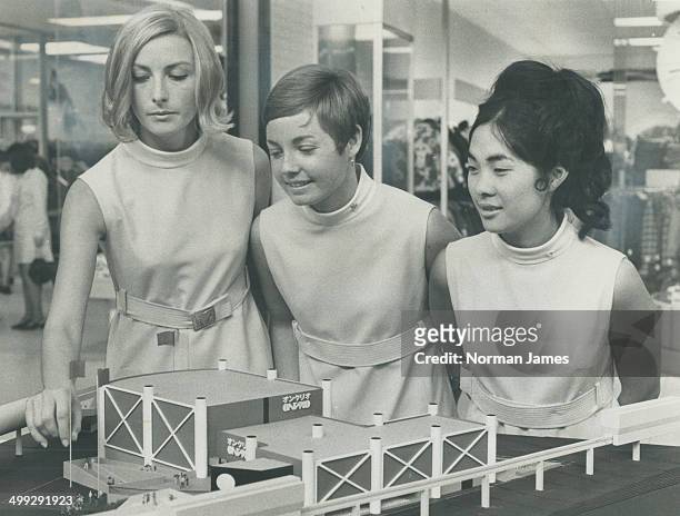 Ricci Richter; Karen Henderson; Kim Morishita with Model of Ontario pavilion. The girls model attractive uniform they will wear in the pavilion at...