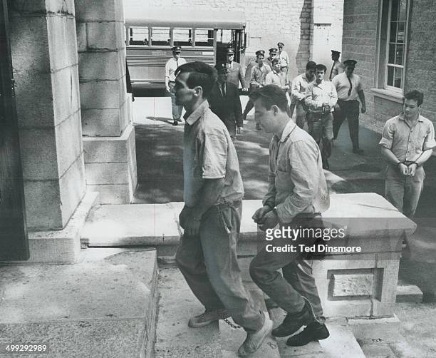 Kingston prisoners with their wrists handcuffed and wearing leg irons shuffle into Frontenao County courthouse yesterday; where the 18 men were...