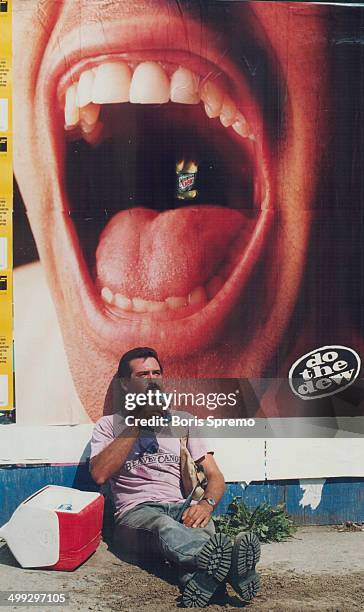 Life imitates advertising. Construction worker Manuel Carreiro takes a sip of soda while resting against a poster promoting another brand of pop...