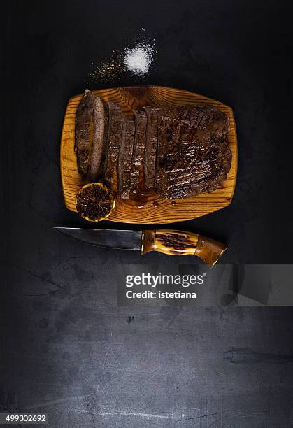 well-done grilled marinated beef flank steak on wooden board with copy space - lob wedge stock-fotos und bilder