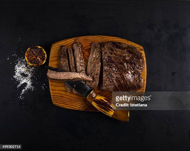 well-done grilled marinated beef flank steak on wooden board - marinated stock pictures, royalty-free photos & images