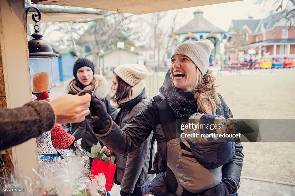 Woman tasting product at an outdoors public market in winter.