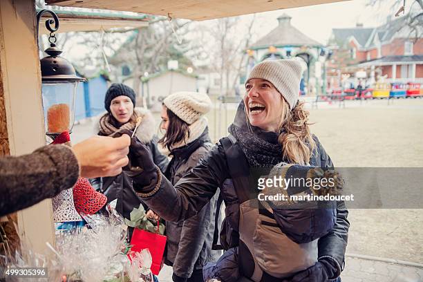 woman tasting product at an outdoors public market in winter. - quebec stock pictures, royalty-free photos & images