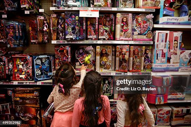 Three girls look at shelves of dolls including Monster High and Ever After High dolls at Toys R Us on La Cienega Blvd., Friday, November 27, 2015.