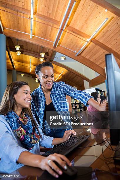 young woman tutoring high school students in library with computers - high tech beauty stockfoto's en -beelden