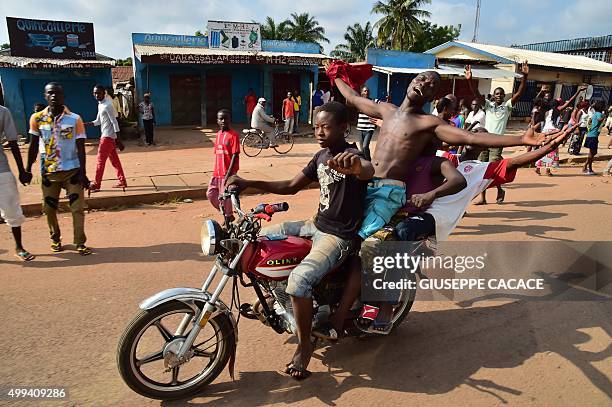 Young men riding a motorbike celebrate in a street of Bangui on November 30, 2015 during a papal visit to Africa. Pope Francis arrived as "a pilgrim...