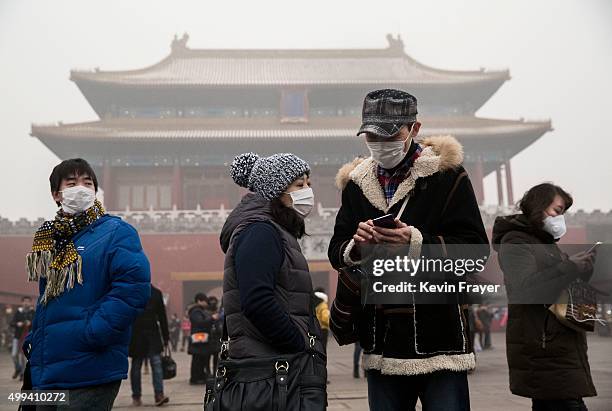 Chinese tourists wear masks as protection from the pollution outside the Forbidden City during a day of high pollution on December 1, 2015 in...