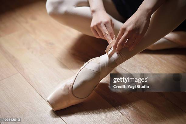 ballerina adjusting shoes - ballettschuh stock-fotos und bilder