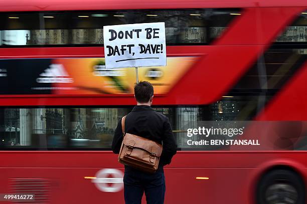 Lone protester opposed to British military action in Syria holds a placard reading 'Don't be daft, Dave!' outside the Houses of Parliament in London...