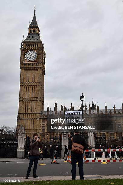 Lone protester opposed to British military action in Syria holds a placard reading 'Don't be daft, Dave!' outside the Houses of Parliament in London...