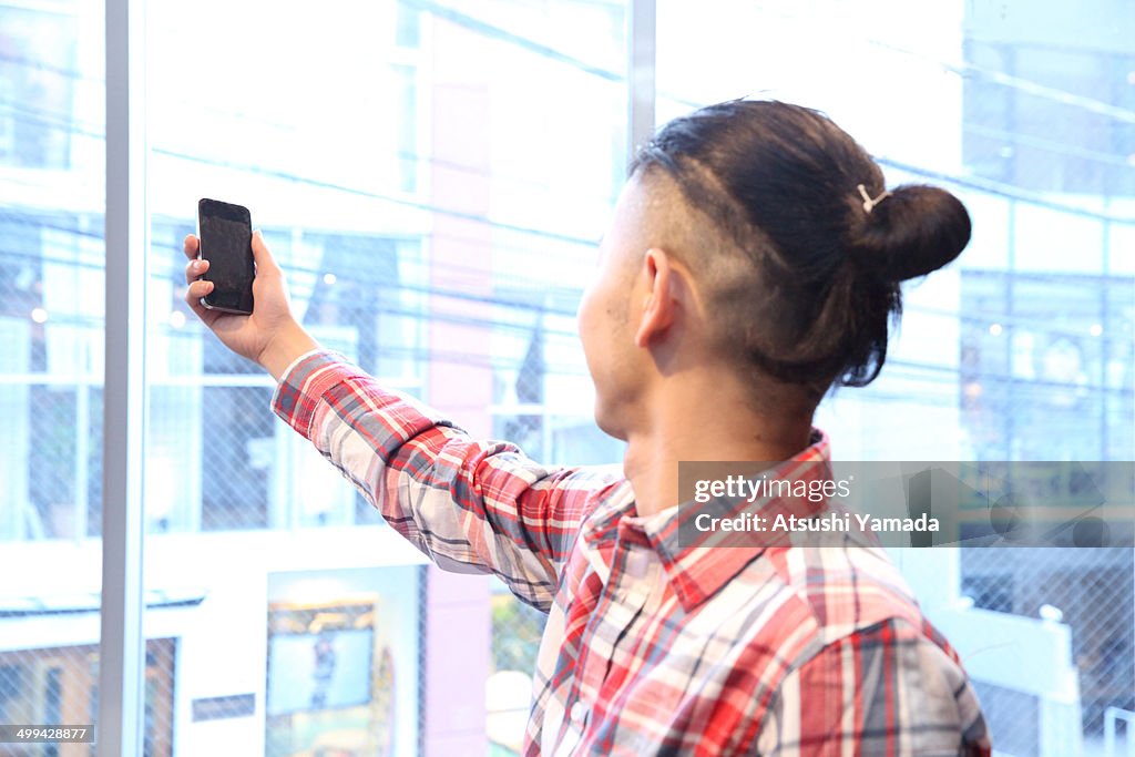 Man holding smartphone near window