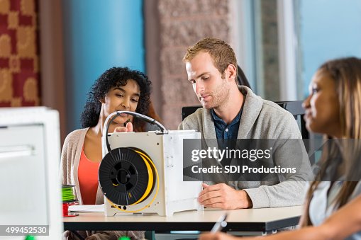 Diverse college classmates creating objects with 3D printer Diverse college classmates creating objects with 3D printer