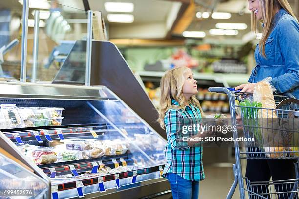 little girl asking mom for something while grocery shopping - deli counter stockfoto's en -beelden