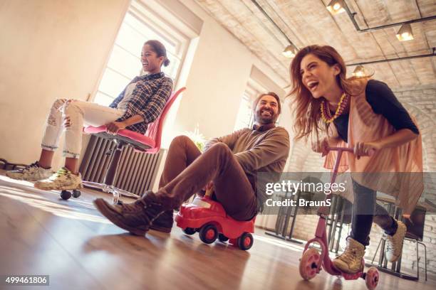 below view of childish people competing in the office. - man on scooter stock pictures, royalty-free photos & images