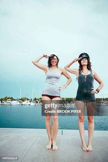 two young women saluting on dock - standing water stock pictures, royalty-free photos & images