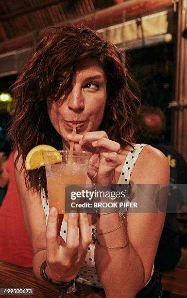 young woman drinking cocktail at bar - cocktails stockfoto's en -beelden