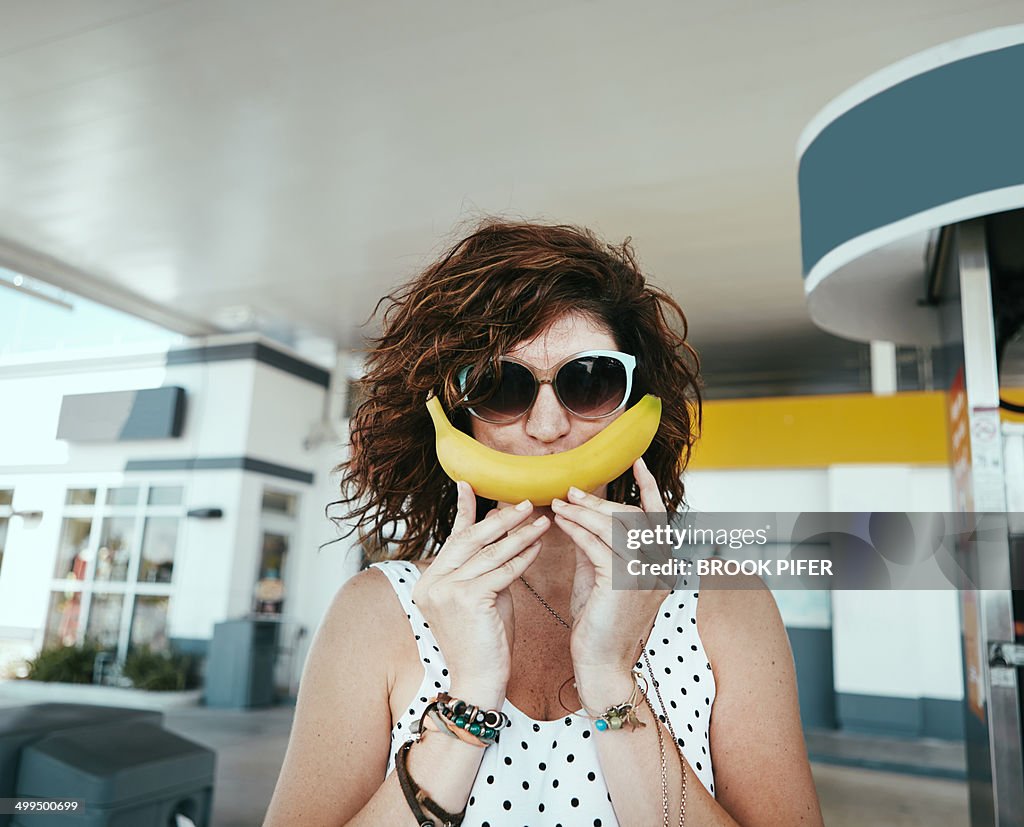 Young woman holding banana up to face as a smile