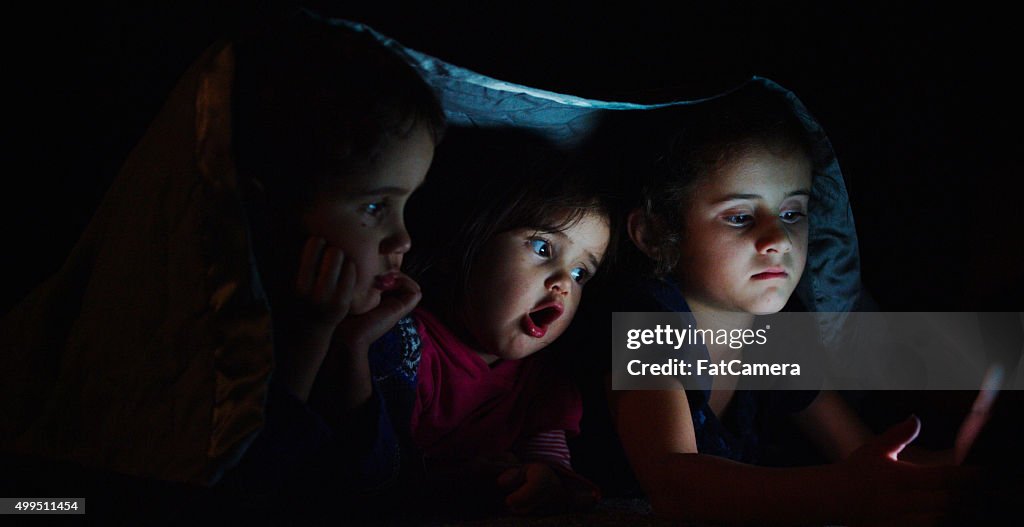 Siblings Watching a Movie Under a Blanket