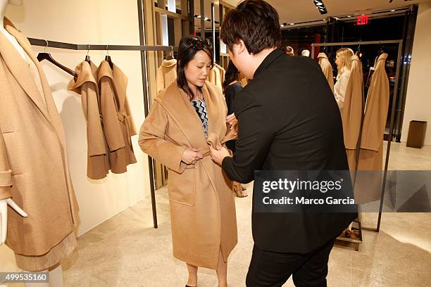 Sales clerk helps Denise Wandasan try on a coat during a party at Max Mara as Max Mara celebrates William Wegman's Dogs in Coats at the store in...