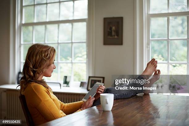 woman using tablet while relaxing in cottage - woman relaxing tablet fotografías e imágenes de stock