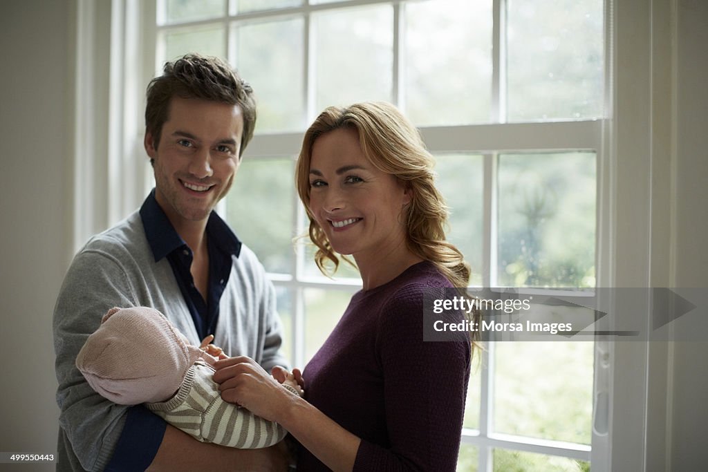 Portrait of happy parents with baby in cottage