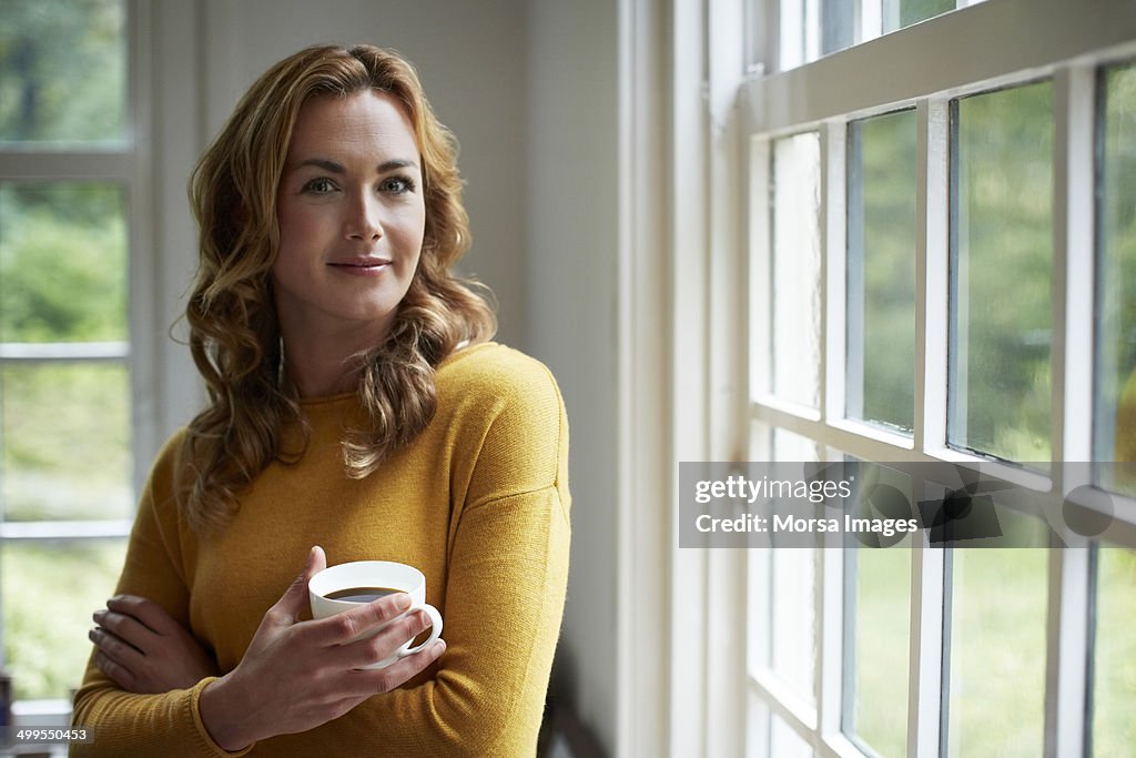 Confident woman having coffee in cottage