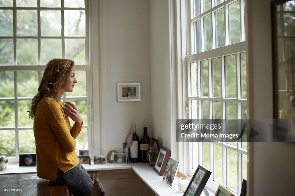Thoughtful woman having coffee in cottage