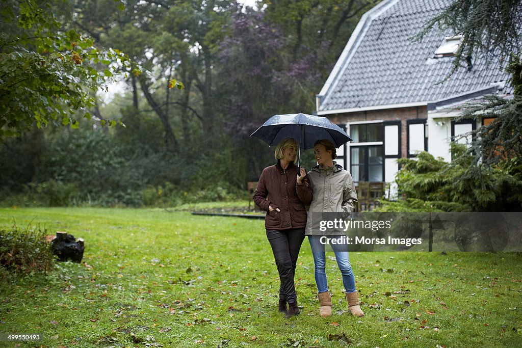 Mother and daughter with umbrella outside cottage