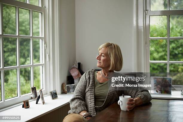 thoughtful senior woman having coffee - sehnsucht lifestyle stock-fotos und bilder