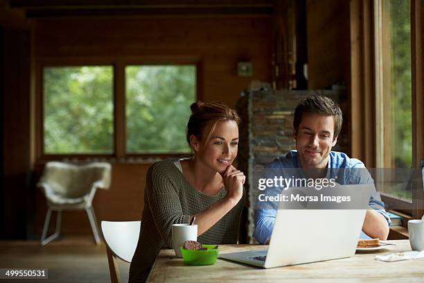 couple using laptop at table in cottage - 2 ladies table computer stock pictures, royalty-free photos & images