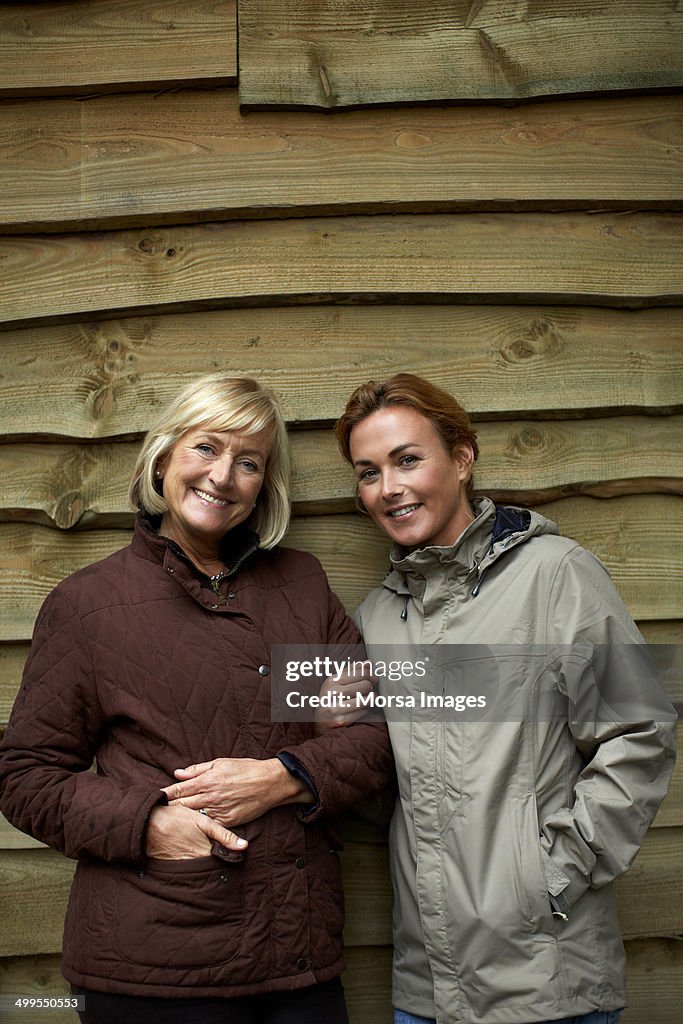 Happy mother and daughter against wooden wall