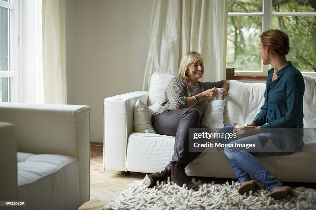 Mother and daughter having coffee on sofa