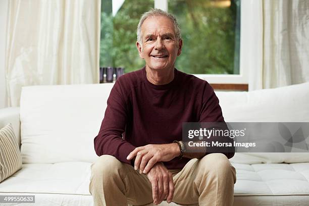 thoughtful senior man looking away on sofa - sitta bildbanksfoton och bilder