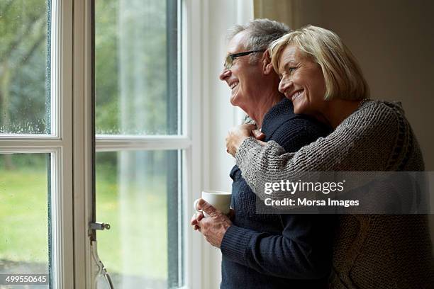 senior woman embracing man in front of door - tranquilidade imagens e fotografias de stock