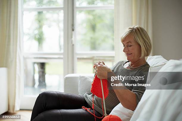 senior woman knitting on sofa - tricoter photos et images de collection