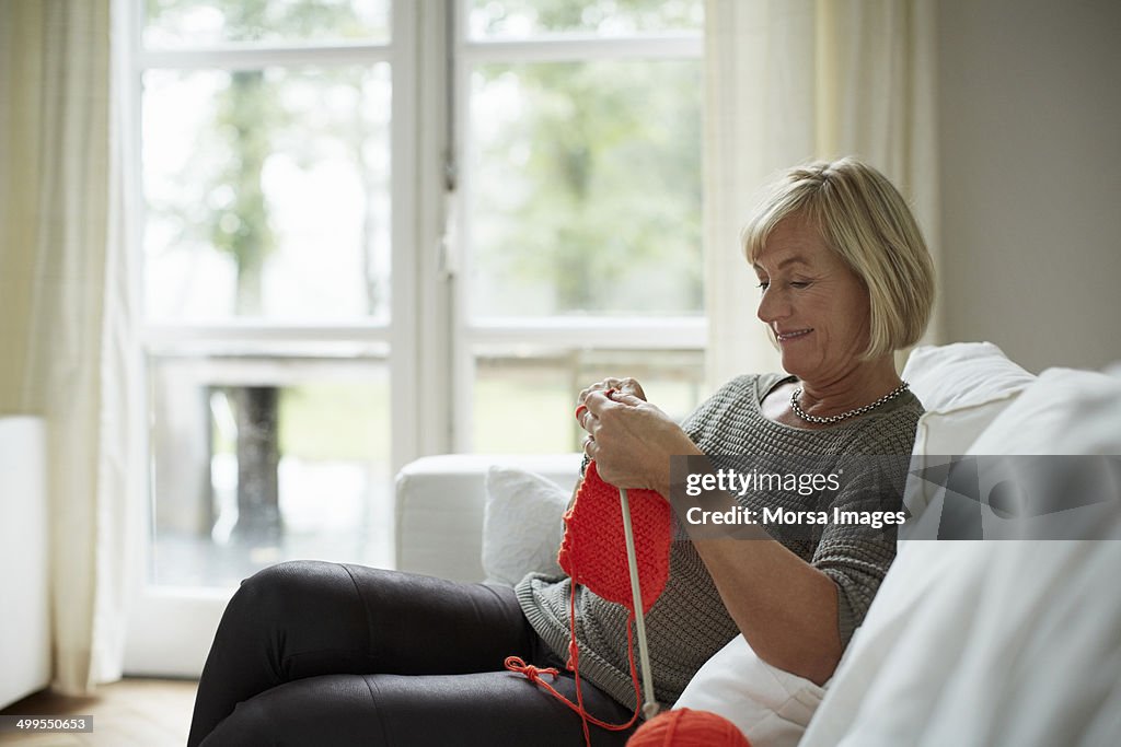 Senior woman knitting on sofa
