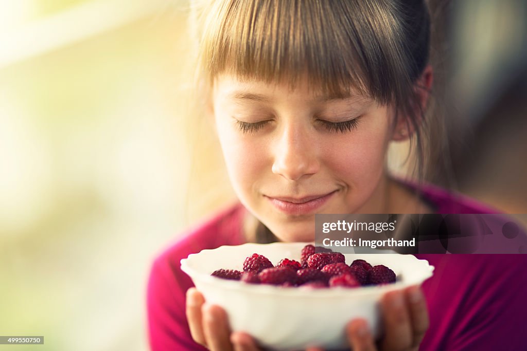 Porträt von einem kleinen Mädchen mit Himbeeren.