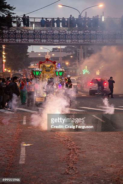 People watch from an overpass as firecrackers are set off on the road during birthday celebrations for the god Qingshan Wang, who is honored during...