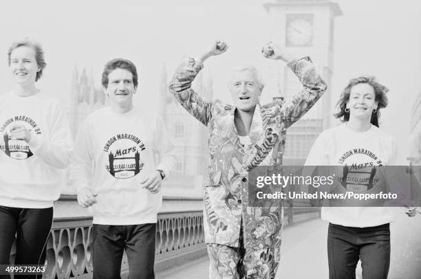 English DJ and television presenter Jimmy Savile pictured running over Westminster Bridge to publicise the upcoming marathon in London on 14th March...
