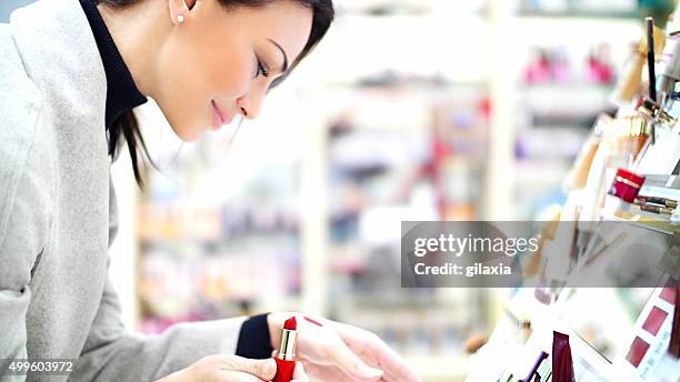 woman choosing a lipstick at beauty store. - lipstick stock pictures, royalty-free photos & images